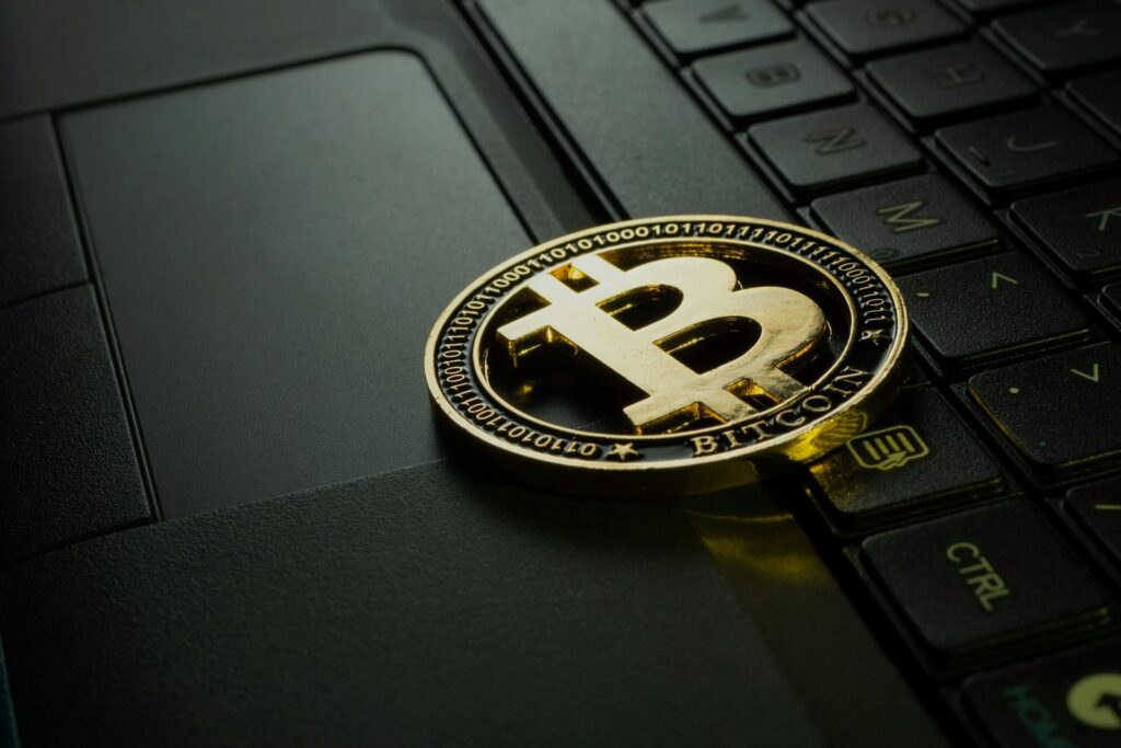 Moeda de bitcoin sobre o teclado de um notebook escuro